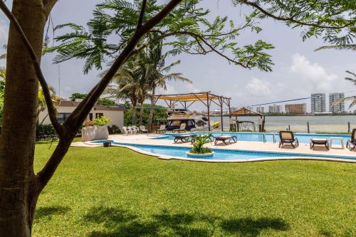a swimming pool in a park with a tree at Villas La Marina in Cancún