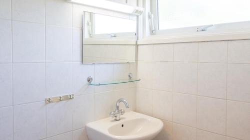 een witte badkamer met een wastafel en een spiegel bij Zeelucht Texel in De Koog