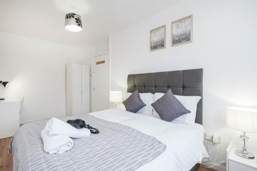 a bedroom with a large white bed with towels on it at Spacious 3-Bedroom House near ExCeL Free Parking E16 in London