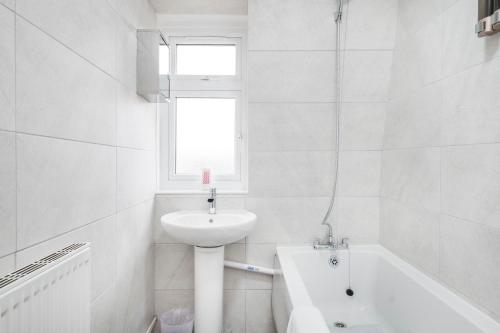 a white bathroom with a sink and a bath tub at Spacious 3-Bedroom House near ExCeL Free Parking E16 in London