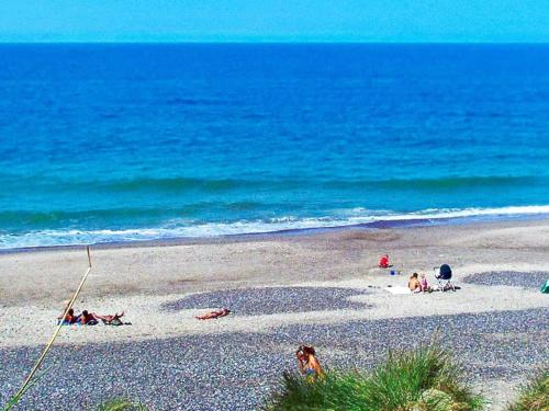 a group of people on a beach near the ocean at 6 person holiday home in Ringkøbing-By Traum in Ringkøbing