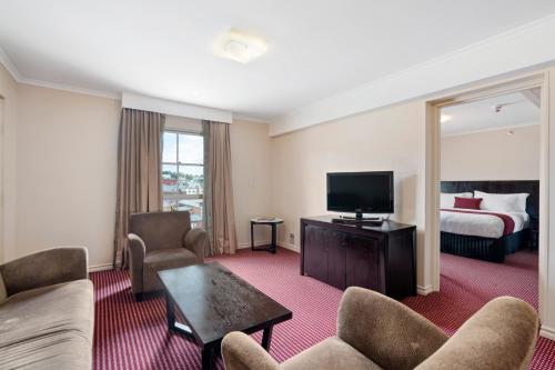 a hotel room with a bed and a living room at Hotel Grand Chancellor Launceston in Launceston