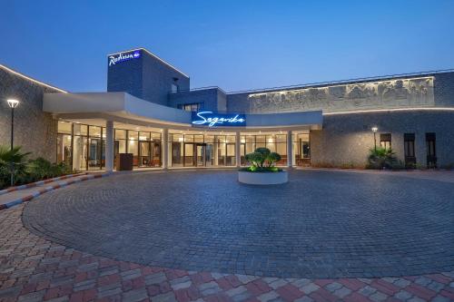 a large building with a courtyard in front of it at Radisson Blu Resort Visakhapatnam in Visakhapatnam