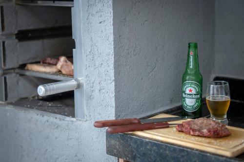 a bottle of beer and some meat and a glass at Villas do Rio 02 in Pôrto de Pedras