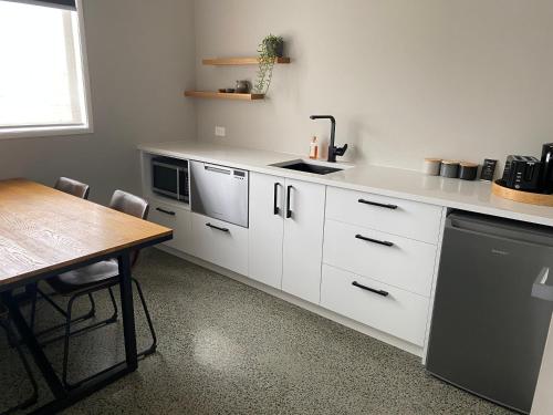 a kitchen with white cabinets and a table and a sink at Northcoast Getaway in Mangawhai