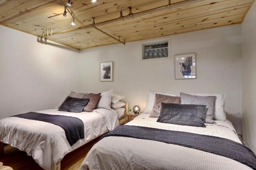 2 camas en una habitación con techos de madera en Lion's Den // Spacious 1500 sqft (2 WC) - Downtown, en Quebec