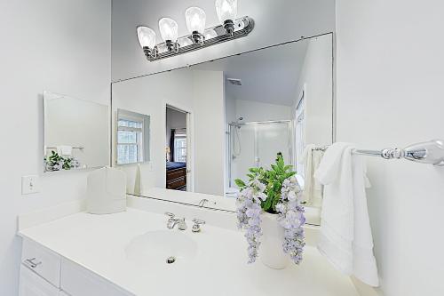 een witte badkamer met een wastafel en een spiegel bij Coral Shells in Ocean Pines