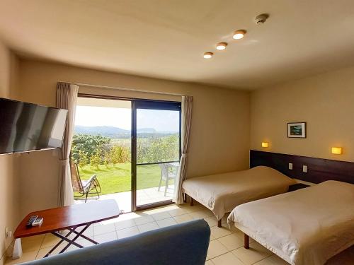 um quarto de hotel com duas camas e uma grande janela em terrace IRIOMOTEJIMA CONDOMINIUM em Iriomote