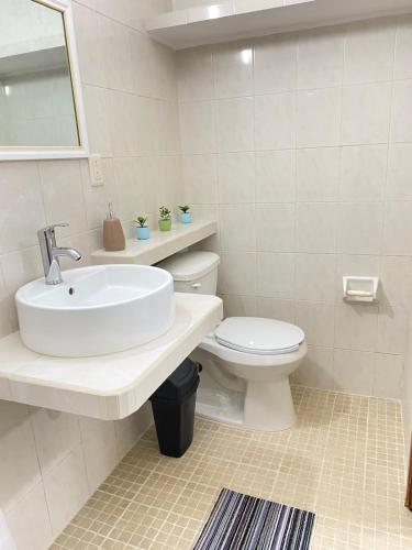 a white bathroom with a sink and a toilet at Departamento Colibrí in Cozumel