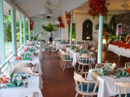 Oualie Beach Resort في نيفيس: غرفة طعام مع طاولات وكراسي بيضاء