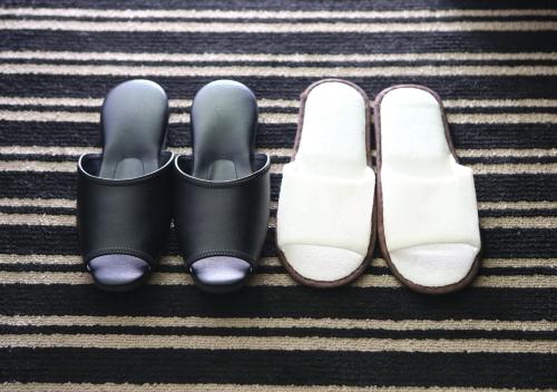 two pairs of shoes sitting on a striped carpet at APA Hotel Miyazaki Eki Tachibanadori in Miyazaki