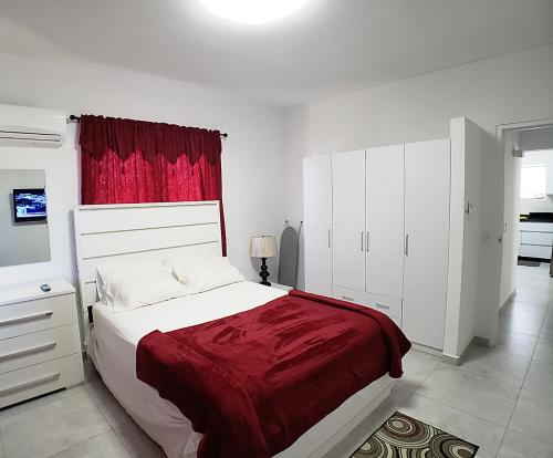 a bedroom with a large bed and a red curtain at Aruba Vacation House - Cozy and Modern! in Oranjestad