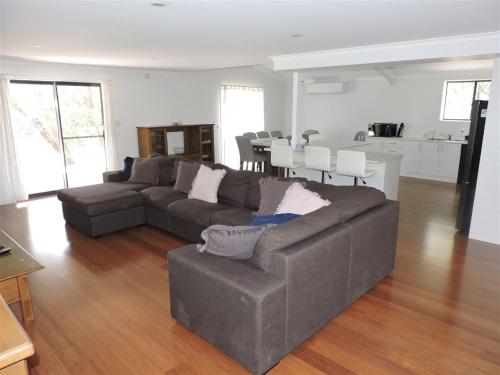 a living room with a gray couch and a kitchen at Paradise on The Boulevard - Beach Holiday Home 