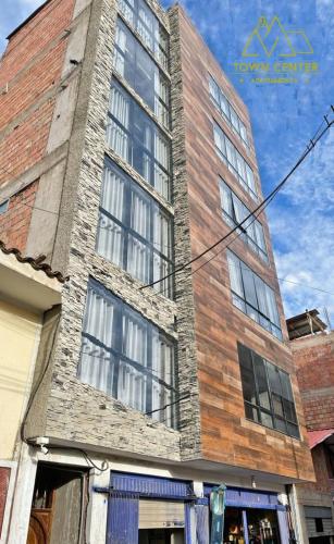 a tall brick building with windows on a street at Town Center Apartments in Urubamba