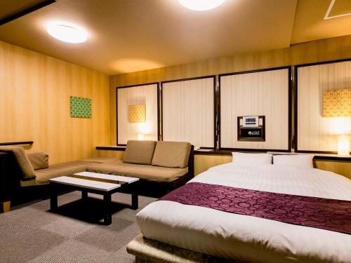 a bedroom with a bed and a couch and a table at A-GATE HOTEL 旭川 -Asahikawa- in Asahikawa