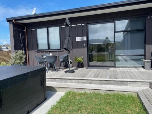 a house with a deck with a table and chairs at Northcoast Getaway in Mangawhai