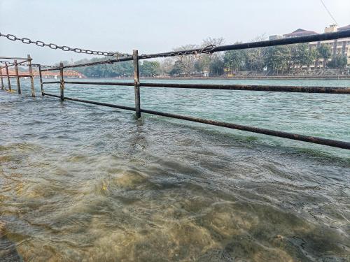 a fence in the water next to a river at Ganga Exotica in Haridwār