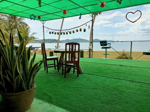 a table and chairs sitting under a green tent next to the beach at Happy Days Resort in Ko Mak