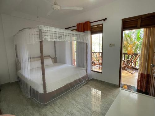 a bedroom with a canopy bed with a balcony at Lake View Villa - Tangalle in Tangalle