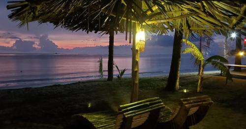 a bench on a beach with the ocean at night at Eagle Bay Retreat Borneo Beach Villas Beach Front in Kumbatang