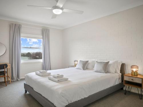 a white bedroom with a large bed and a window at Finchs Nest in Moss Vale