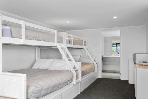 a white bedroom with two bunk beds in it at Acacia Bay in Taupo