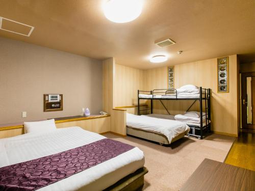 a room with two beds and a bunk bed at A-GATE HOTEL 旭川 -Asahikawa- in Asahikawa