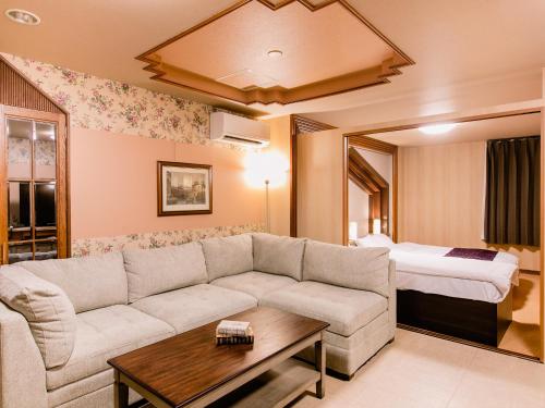 a living room with a couch and a bed at A-GATE HOTEL 旭川 -Asahikawa- in Asahikawa