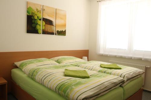 a bed with two green pillows on it in a room at Penzion Bobule in Staré Město