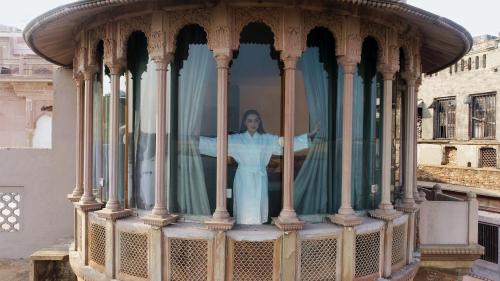 a woman standing behind a curtain in a gazebo at BrijRama Palace, Varanasi - By the Ganges in Varanasi