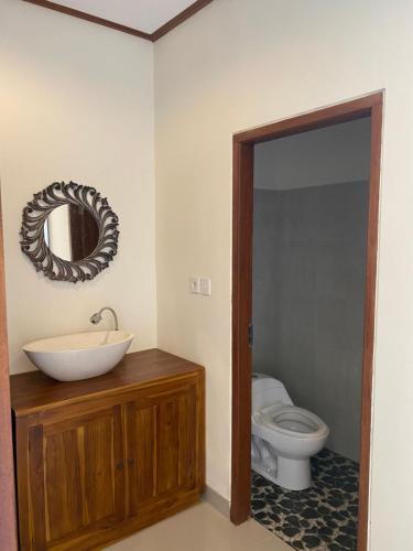 uma casa de banho com um WC, um lavatório e um espelho. em Sambahan Inn em Ubud