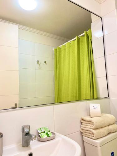 a bathroom with a green shower curtain and a sink at Apartamentos Alma Socoroma in Arica