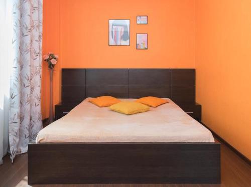 ノヴォシビルスクにあるApartment on Kirovaのベッドルーム1室(オレンジ色の壁のベッド1台付)