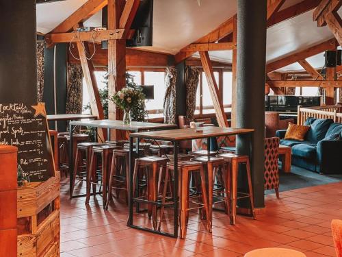 een restaurant met houten tafels en krukken bij Hôtel Le Montana in La Tania