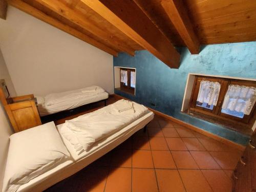 2 camas en una habitación con 2 ventanas en Appartamento Pieve, en Pieve Tesino