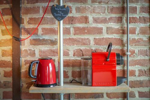 a red appliance on a shelf next to a brick wall at B&B Bij Tante Toos in Lemiers