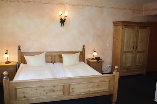 una camera da letto con un letto con lenzuola bianche e due lampade di Hotel zum Ritter Nidderau a Nidderau