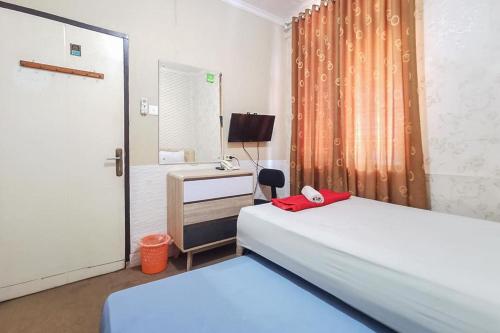 a bedroom with two beds and a desk and a mirror at Good Sleep Balikpapan Mitra RedDoorz in Balikpapan