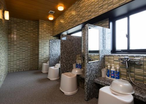 a bathroom with a row of toilets and sinks at Manten no Yu Michi no Yado in Nonoichi