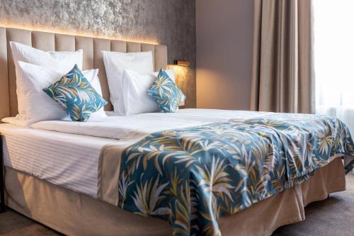 a large bed with blue and white sheets and pillows at JOYME Hotel in Sibiu