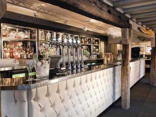 a bar in a restaurant with a man standing behind the counter at The Blue Anchor in Feering