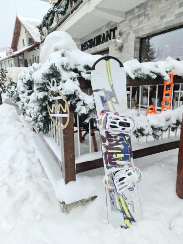 a snowboard is standing in the snow in front of a building at Pensiune Rara Paltinis in Păltiniş