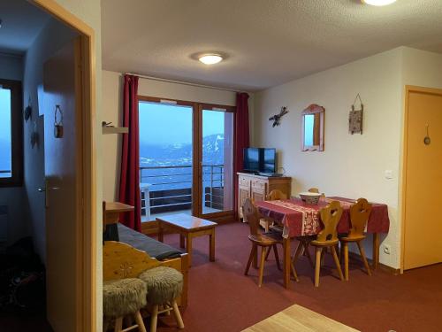 een woonkamer met een tafel en stoelen en een raam bij Le Corbier résidence Les Pistes in Le Corbier