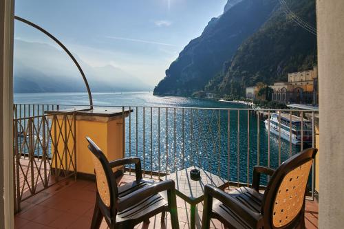 a balcony with two chairs and a view of the water at Hotel Sole Relax & Panorama in Riva del Garda
