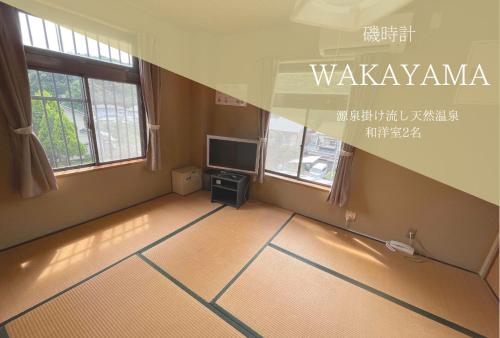 an empty living room with a television and windows at Hotel Isodokei in Shirahama