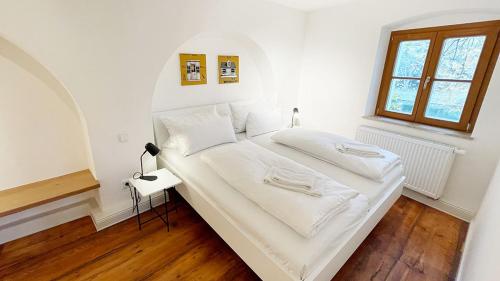 a bedroom with a bed with white sheets and a window at Wassergasse 11 in Regensburg