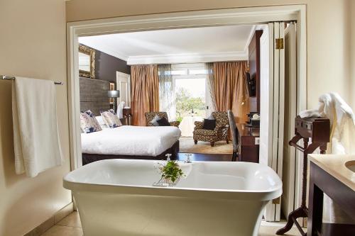 a bathroom with a bath tub and a bedroom at The Devon Valley Hotel in Stellenbosch