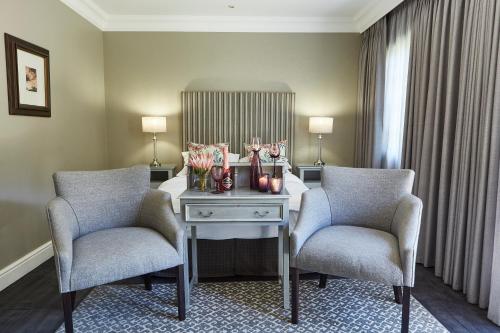 a room with two chairs and a table with a mirror at The Devon Valley Hotel in Stellenbosch