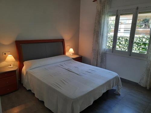 um quarto com uma cama com 2 candeeiros e uma janela em Chalet I con terraza en la playa em San Pedro del Pinatar
