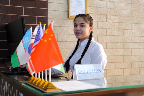 a woman standing in front of a table with flags at Hotel Jasmina in Samarkand